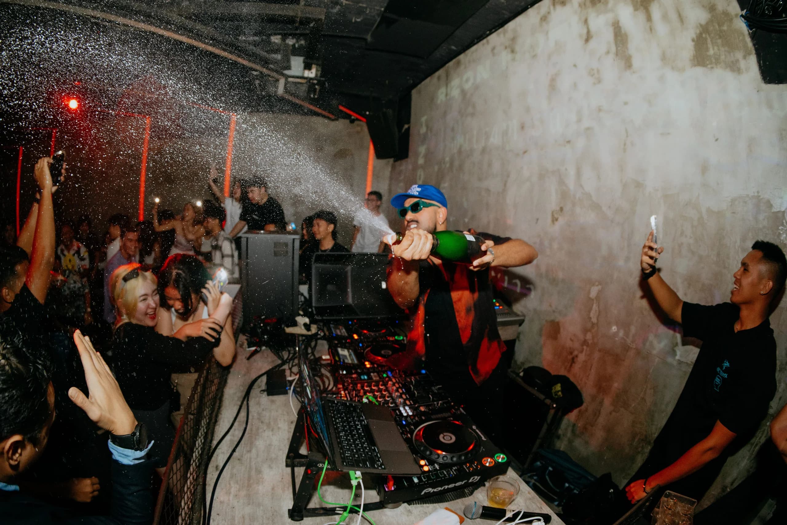 A DJ spraying champagne over a packed dance floor